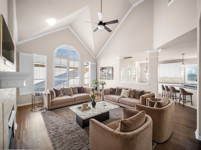 living room with ceiling fan with notable chandelier, dark hardwood / wood-style flooring, high vaulted ceiling, and ornate columns