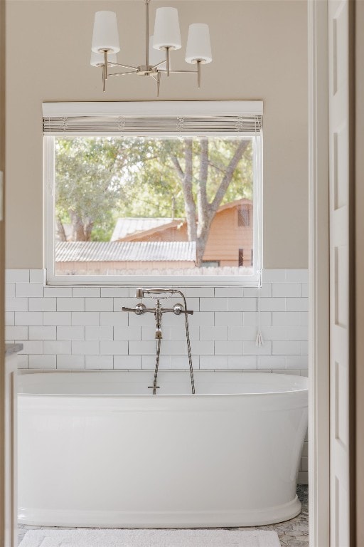 bathroom with a tub to relax in, tile walls, and a notable chandelier