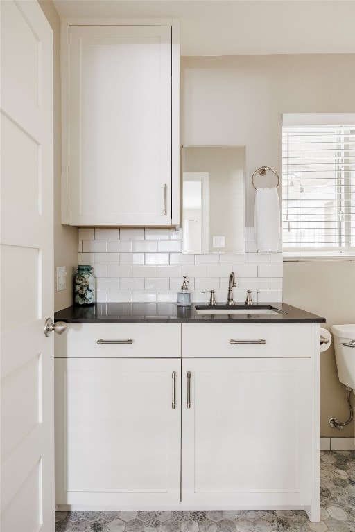 kitchen with white cabinets, decorative backsplash, and sink