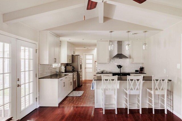 kitchen featuring decorative light fixtures, tasteful backsplash, white cabinetry, and wall chimney exhaust hood