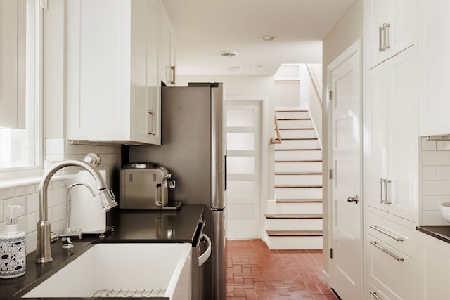 kitchen with decorative backsplash, white cabinetry, and sink