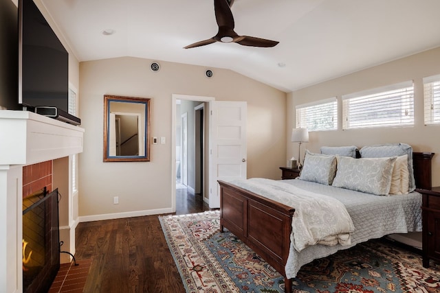 bedroom featuring ceiling fan, a fireplace, dark wood-type flooring, and vaulted ceiling