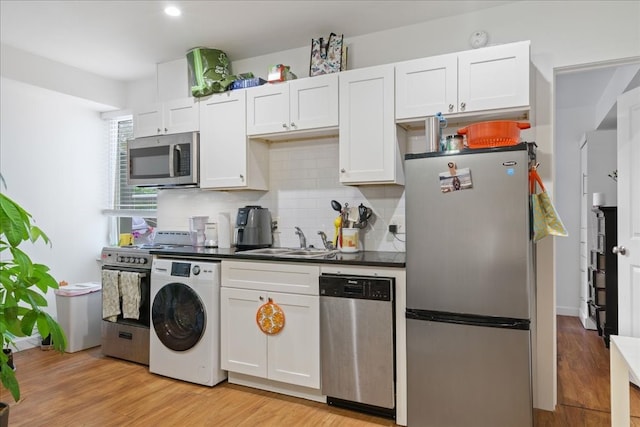 kitchen with white cabinets, sink, light hardwood / wood-style flooring, stainless steel appliances, and washer / clothes dryer