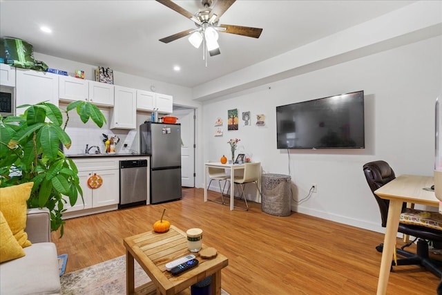 living room featuring light hardwood / wood-style flooring, ceiling fan, and sink