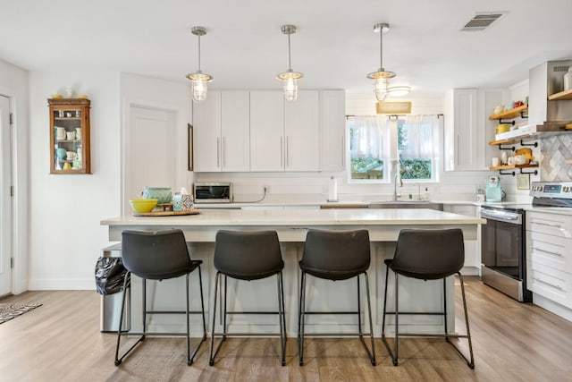 kitchen featuring white cabinets, a center island, stainless steel electric stove, and sink