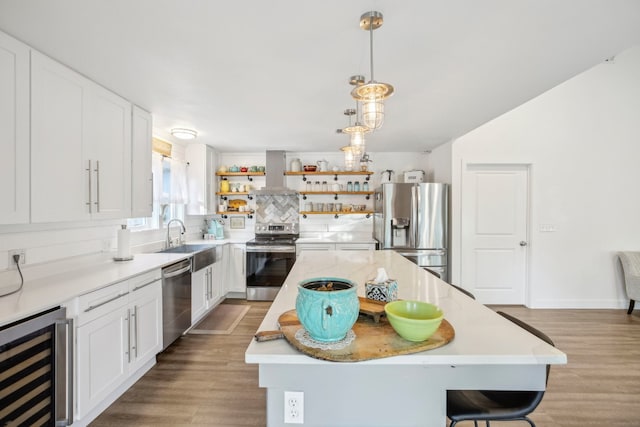 kitchen with a center island, white cabinets, wall chimney range hood, appliances with stainless steel finishes, and beverage cooler