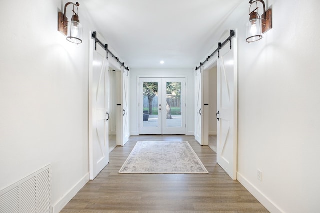 doorway with a barn door, french doors, and wood-type flooring