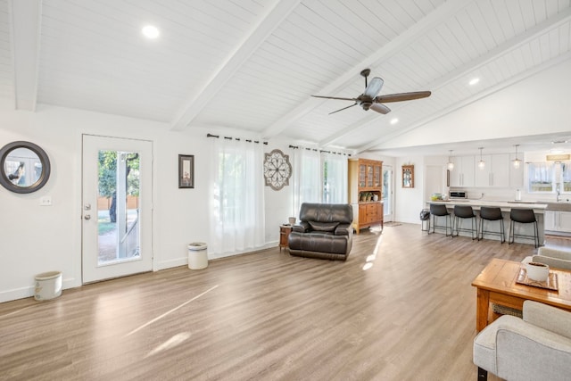 living room featuring vaulted ceiling with beams, a wealth of natural light, and light hardwood / wood-style floors