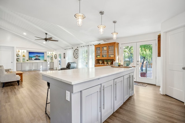 kitchen featuring french doors, lofted ceiling with beams, hanging light fixtures, light hardwood / wood-style flooring, and ceiling fan