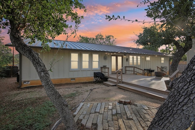 back house at dusk featuring a wooden deck