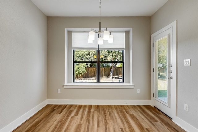 unfurnished dining area featuring light hardwood / wood-style floors and a chandelier