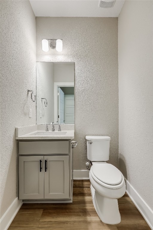 bathroom with hardwood / wood-style floors, vanity, and toilet