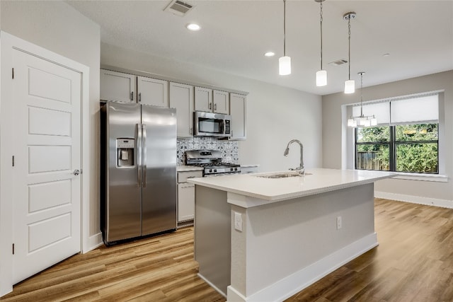 kitchen with an island with sink, stainless steel appliances, and light hardwood / wood-style floors