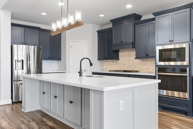 kitchen featuring stainless steel refrigerator with ice dispenser, sink, gas cooktop, an island with sink, and hardwood / wood-style floors