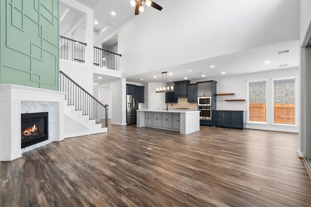 unfurnished living room featuring dark wood-type flooring, ceiling fan, and sink