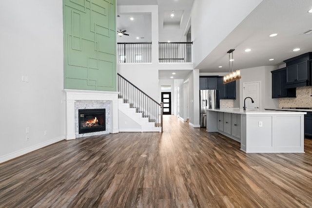 unfurnished living room with dark hardwood / wood-style flooring, sink, a towering ceiling, and ceiling fan