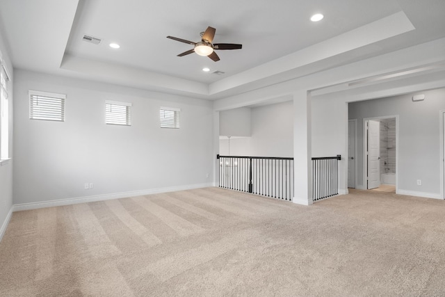 carpeted spare room with ceiling fan and a tray ceiling