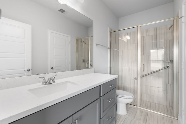 bathroom with vanity, toilet, and a shower with door