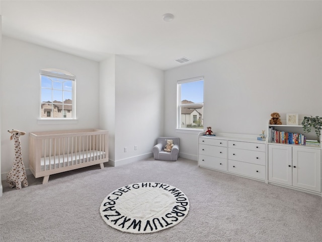 bedroom featuring multiple windows, light carpet, and a nursery area