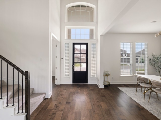 foyer entrance with dark hardwood / wood-style floors and a towering ceiling