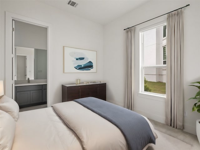 carpeted bedroom featuring connected bathroom and sink