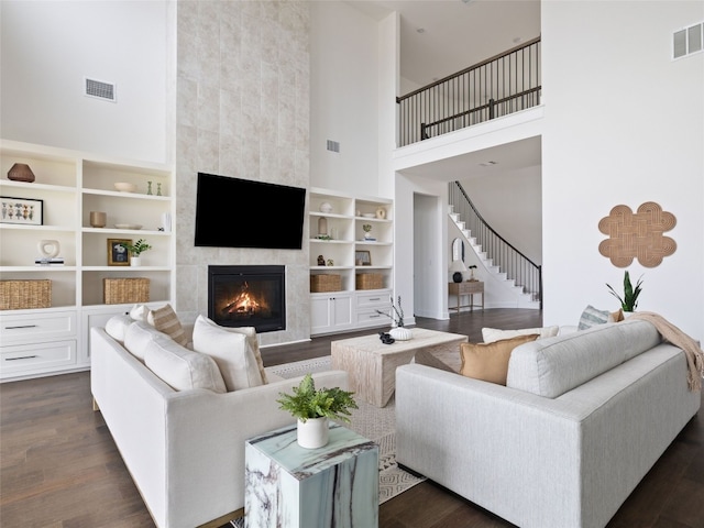 living room with a tile fireplace, dark hardwood / wood-style floors, and a high ceiling