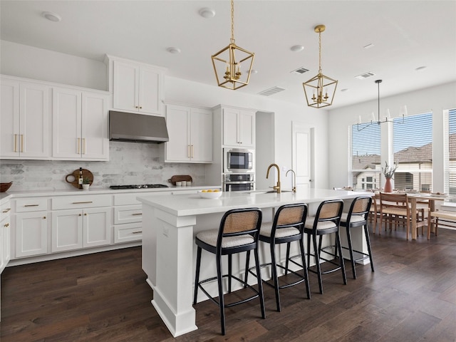 kitchen with white cabinets, dark hardwood / wood-style flooring, a kitchen island with sink, and hanging light fixtures