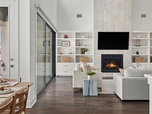 living room with a tile fireplace, dark hardwood / wood-style floors, and built in features