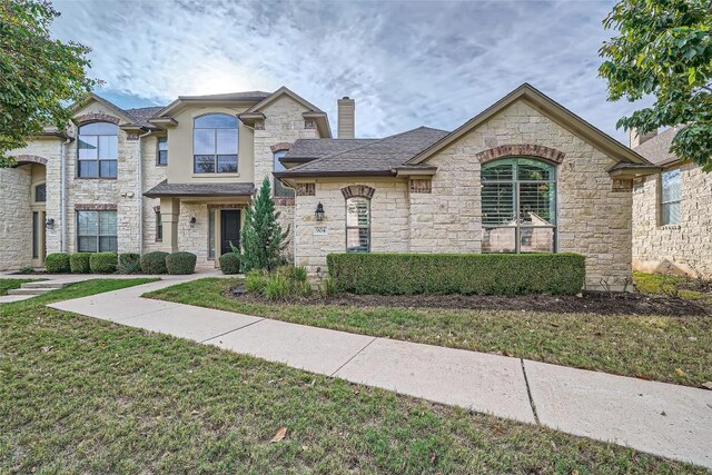 french country inspired facade with a front yard