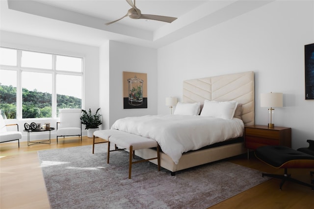 bedroom featuring hardwood / wood-style floors, a raised ceiling, and ceiling fan