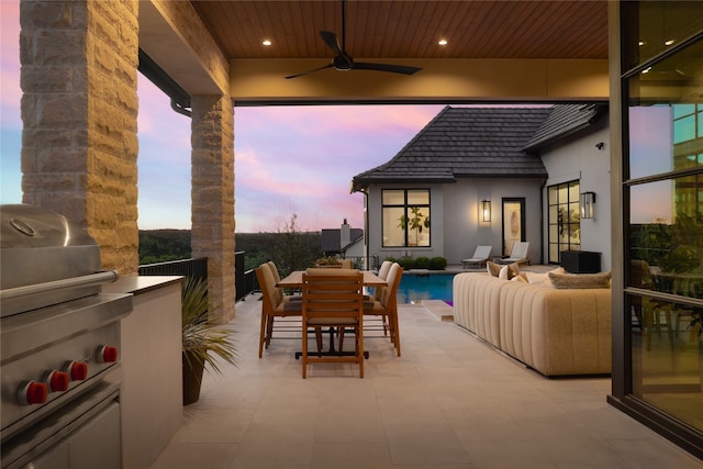 patio terrace at dusk featuring ceiling fan and a grill