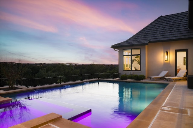 pool at dusk featuring a patio