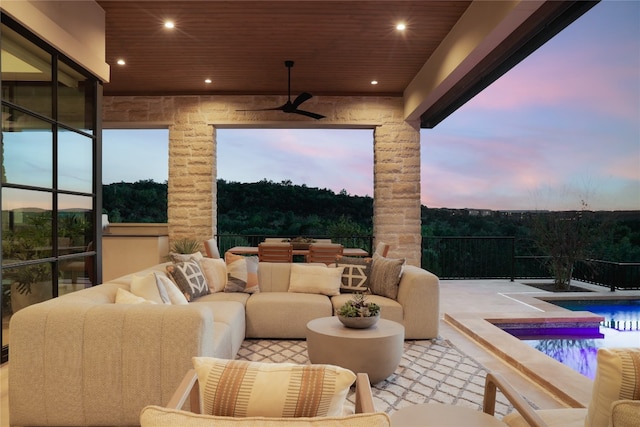 patio terrace at dusk featuring ceiling fan, a fenced in pool, and an outdoor living space