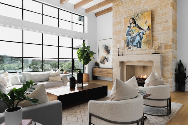 interior space with a fireplace, beamed ceiling, light hardwood / wood-style floors, and a high ceiling