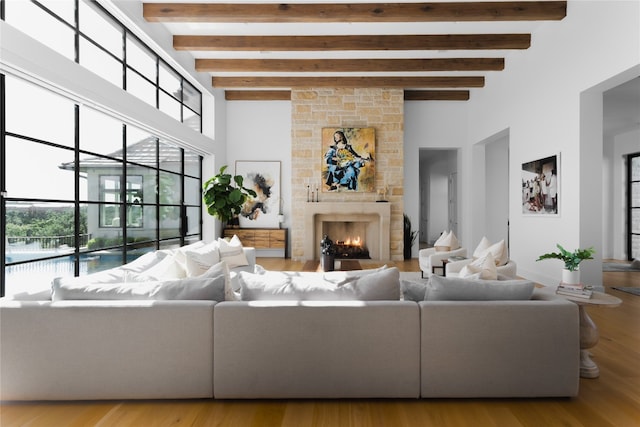 living room with hardwood / wood-style flooring, beam ceiling, a towering ceiling, and a fireplace