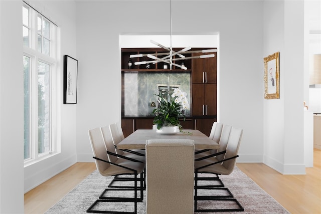 dining area with hardwood / wood-style floors, a healthy amount of sunlight, and a notable chandelier