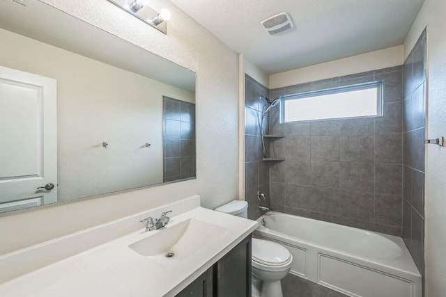 full bathroom featuring tiled shower / bath combo, vanity, and toilet