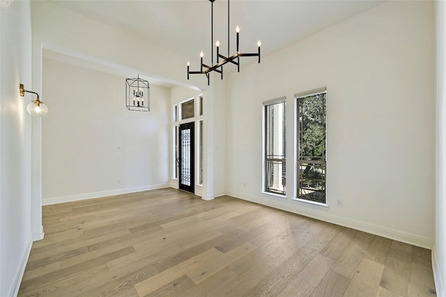 unfurnished dining area with light wood-type flooring and a chandelier