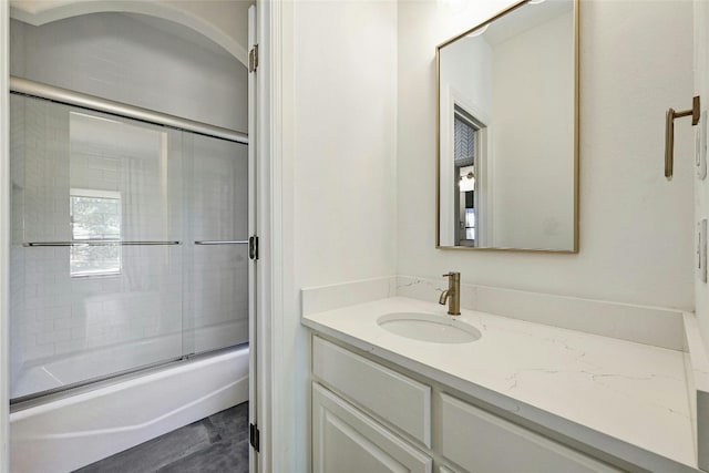 bathroom featuring combined bath / shower with glass door and vanity