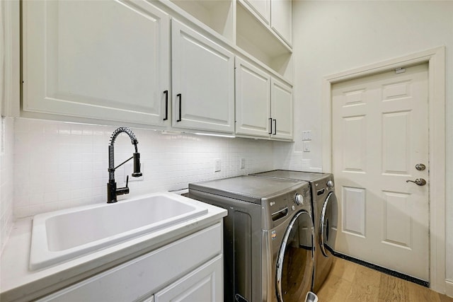 laundry room with washer and dryer, sink, cabinets, and light hardwood / wood-style floors