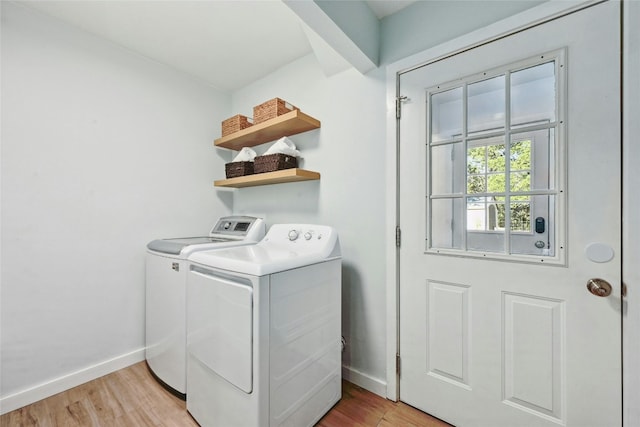 clothes washing area featuring light wood-type flooring and separate washer and dryer