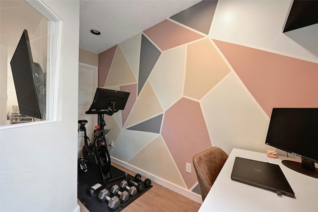 exercise room with wood-type flooring and a textured ceiling