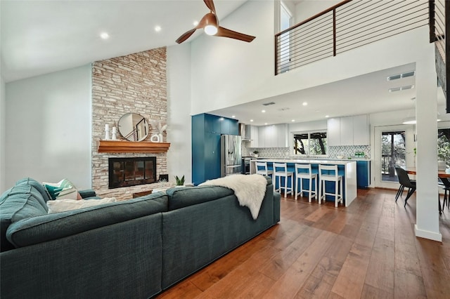 living room featuring a fireplace, ceiling fan, dark hardwood / wood-style flooring, and a high ceiling