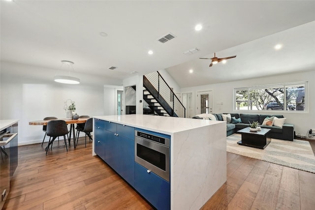 kitchen with hardwood / wood-style floors, lofted ceiling, a center island, and blue cabinets