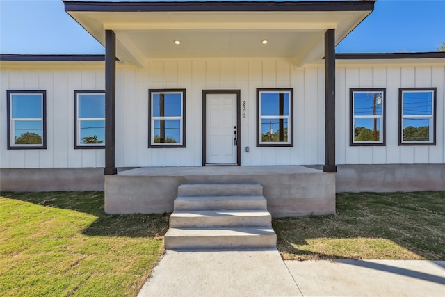 property entrance with covered porch and a lawn