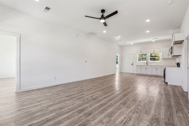 unfurnished living room with ceiling fan, light hardwood / wood-style floors, and sink