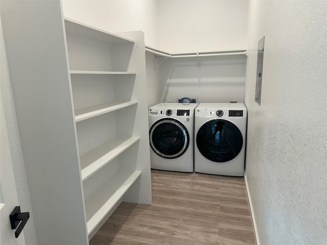 clothes washing area with separate washer and dryer, electric panel, and light wood-type flooring