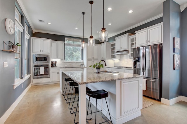 kitchen with an island with sink, decorative backsplash, a breakfast bar, white cabinets, and appliances with stainless steel finishes