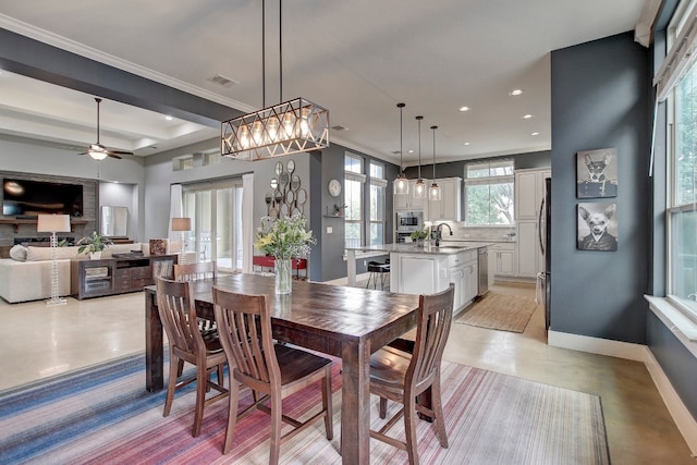 dining area with ceiling fan, ornamental molding, and sink