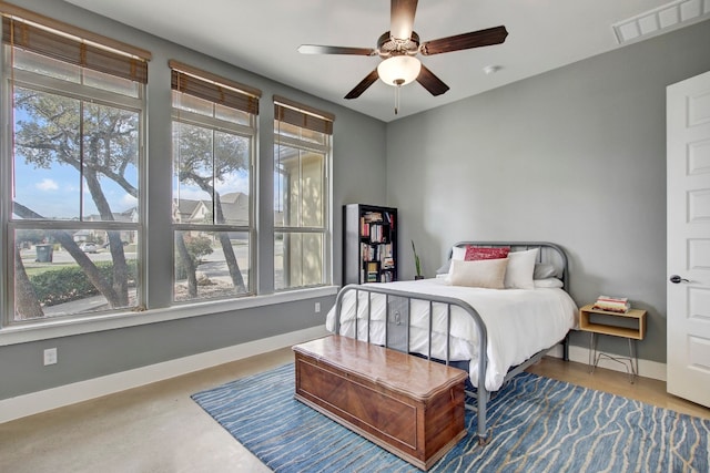 bedroom featuring ceiling fan, concrete flooring, and multiple windows